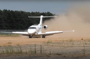 Image of a plane landing on a gravel runway